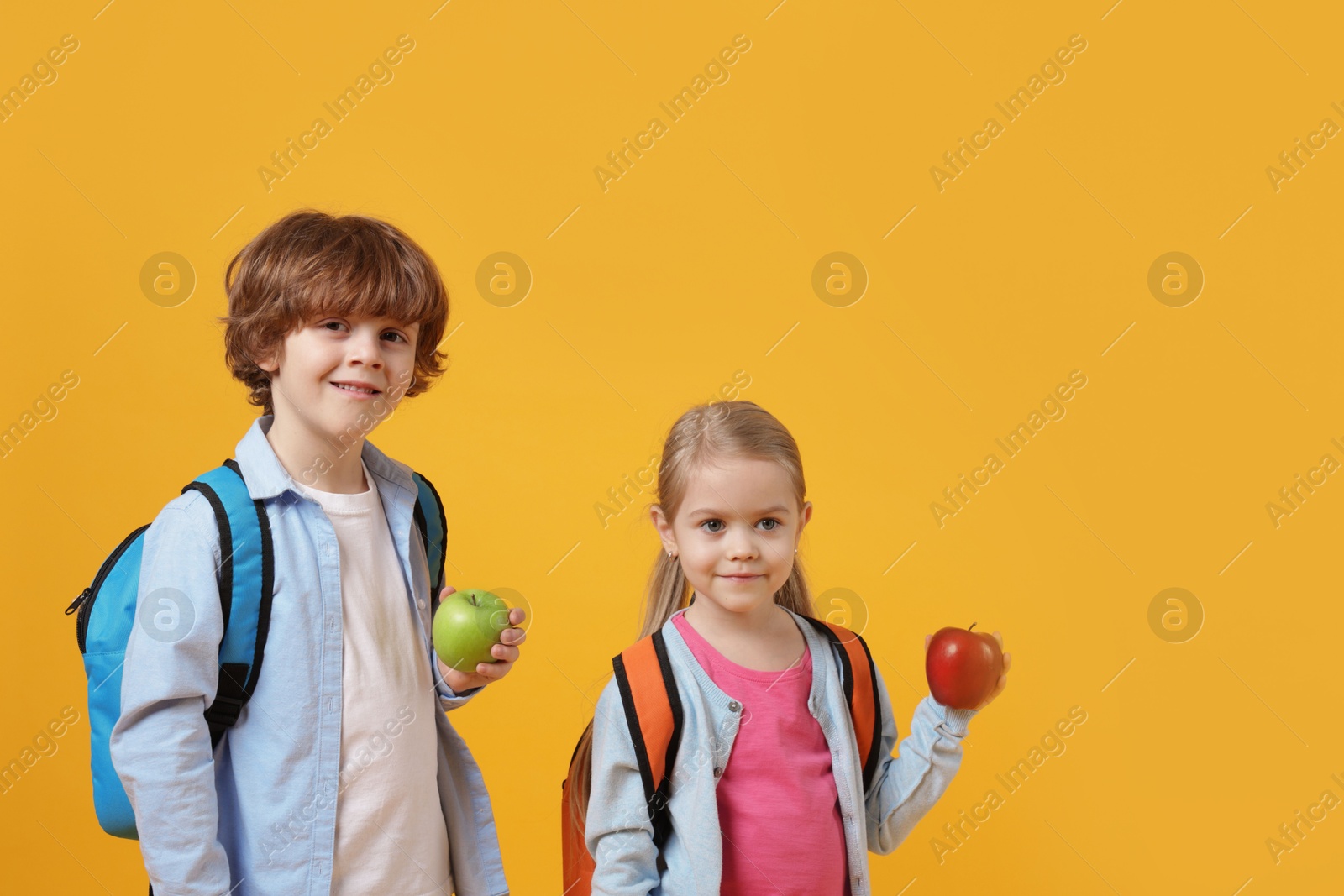 Photo of School children with apples on orange background. Space for text