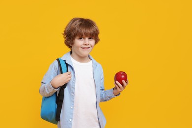 Photo of Little boy with apple on orange background. Space for text