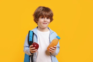 Photo of Little boy with apple and drink on orange background