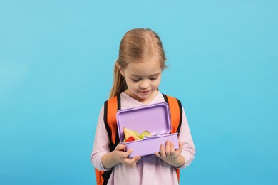 Photo of Cute little girl with lunch box on light blue background