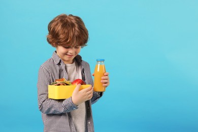 Cute little boy with lunch box and drink on light blue background. Space for text