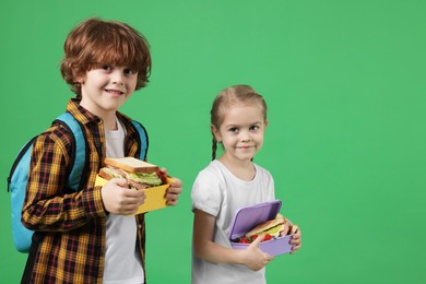 Cute little children with lunch boxes on green background. Space for text