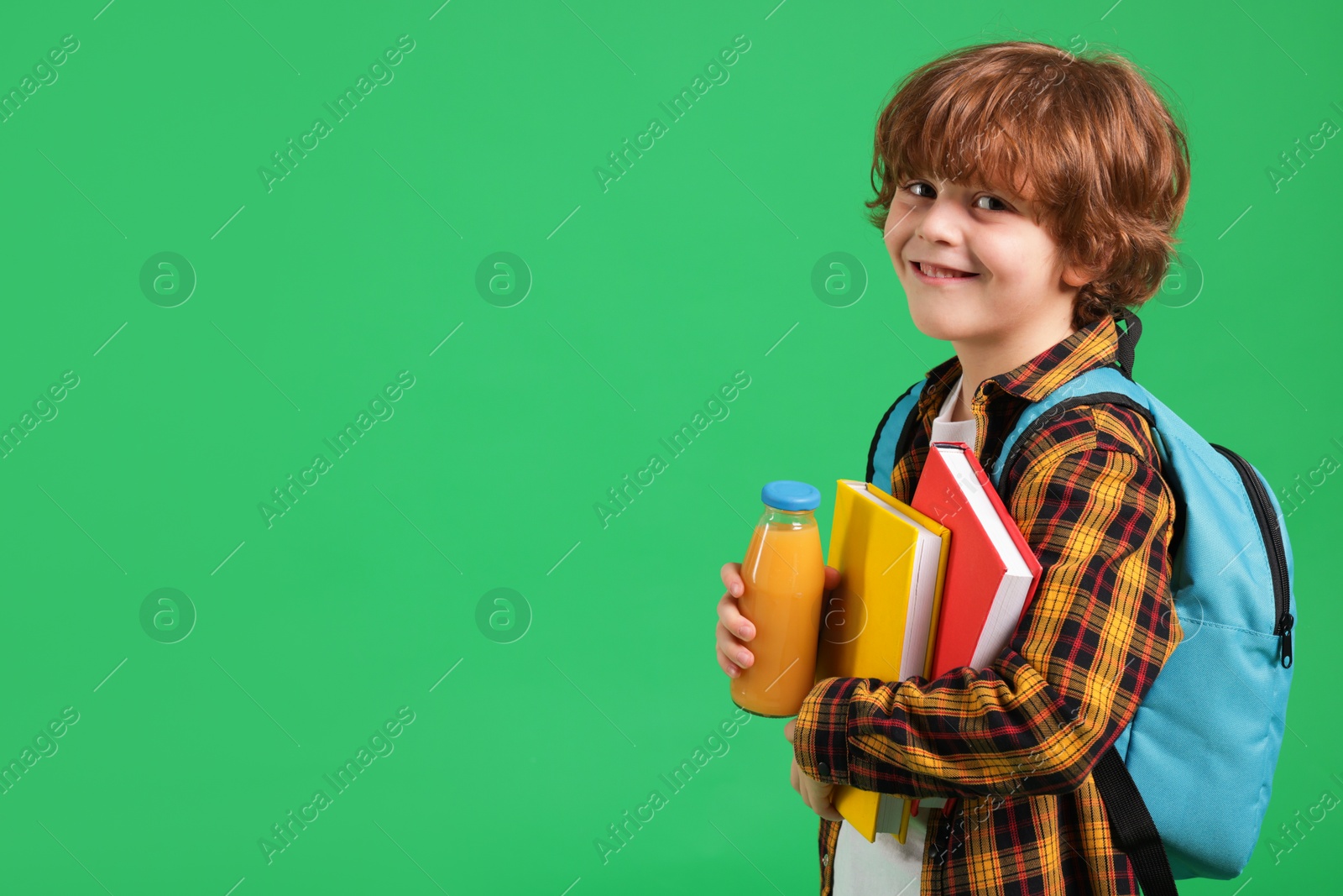 Photo of Cute little boy with books and drink on green background. Space for text