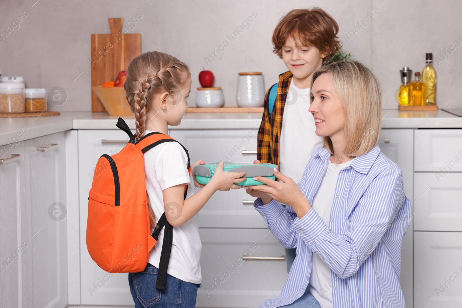 Photo of Mother giving her children lunch in kitchen