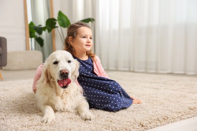 Photo of Little girl with cute dog on carpet at home