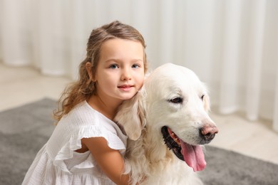 Photo of Little girl with cute dog on carpet at home