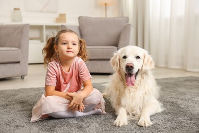 Photo of Little girl with cute dog on carpet at home