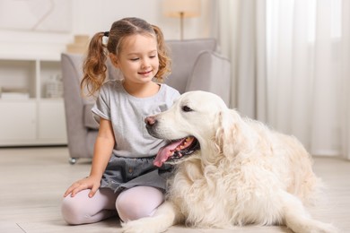 Little girl with cute dog on floor at home