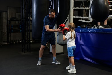 Boxing coach training girl in sport center