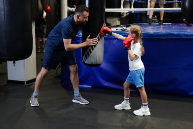 Boxing coach training girl in sport center