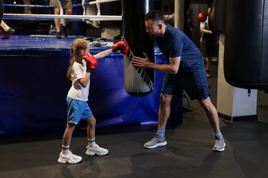 Boxing coach training girl in sport center