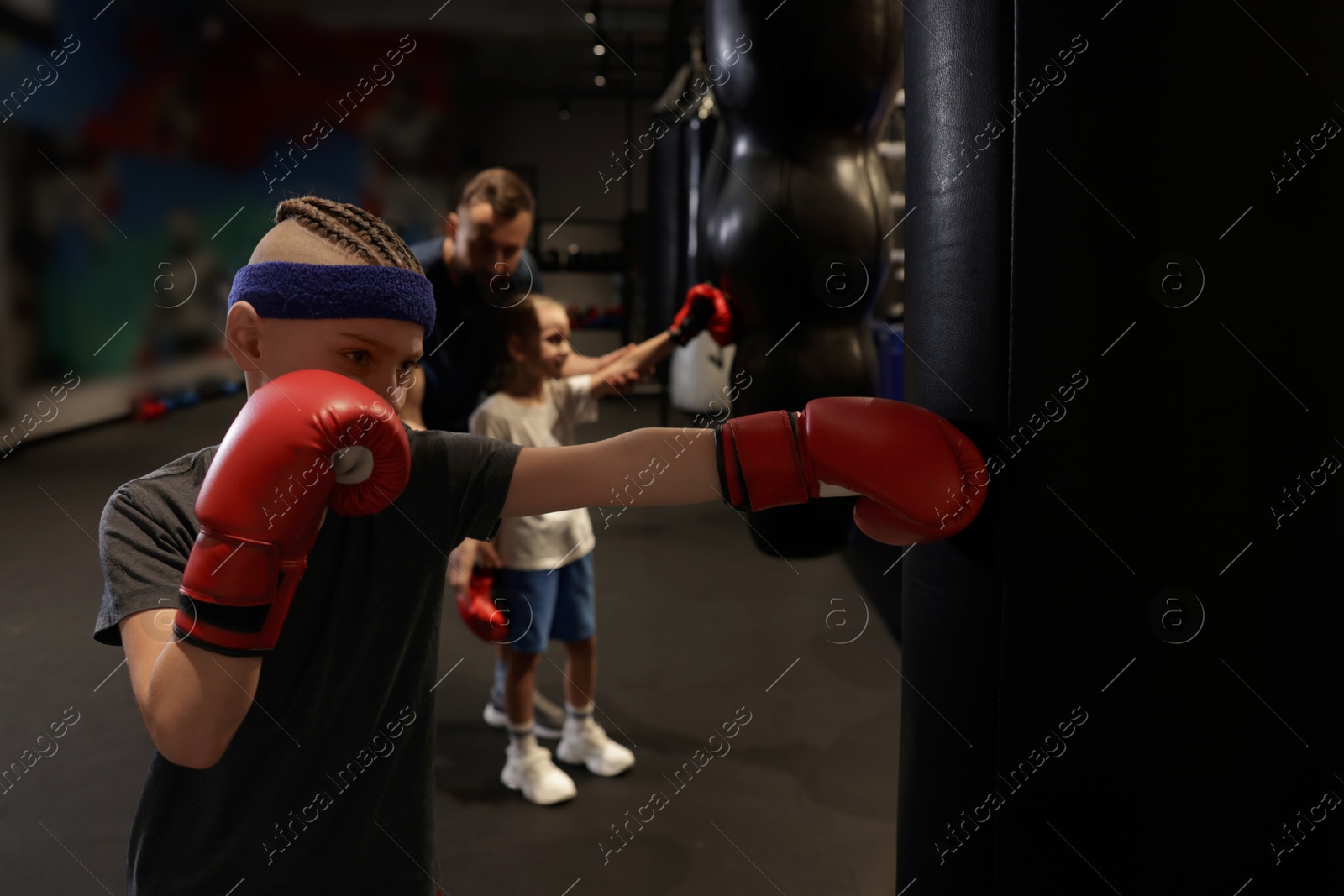 Photo of Children having boxing practice with their coach in training center, selective focus