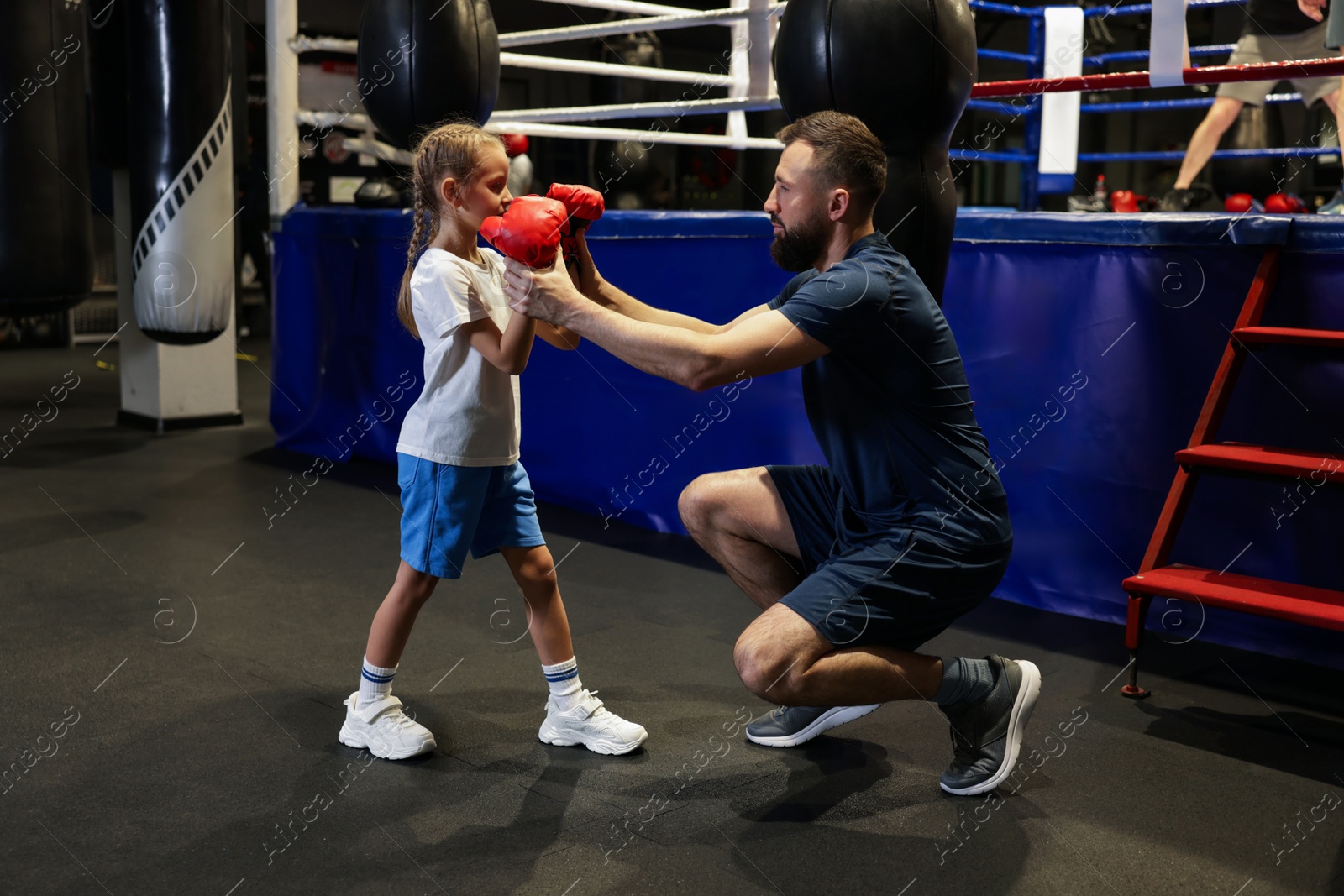 Photo of Boxing coach training girl in sport center