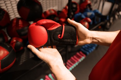 Man holding protective boxing glove indoors, closeup