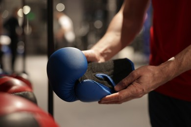 Man holding protective boxing glove indoors, closeup