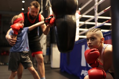 Photo of Children having boxing practice with their coach in training center, selective focus