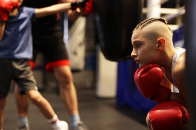 Photo of Children having boxing practice with their coach in training center, selective focus