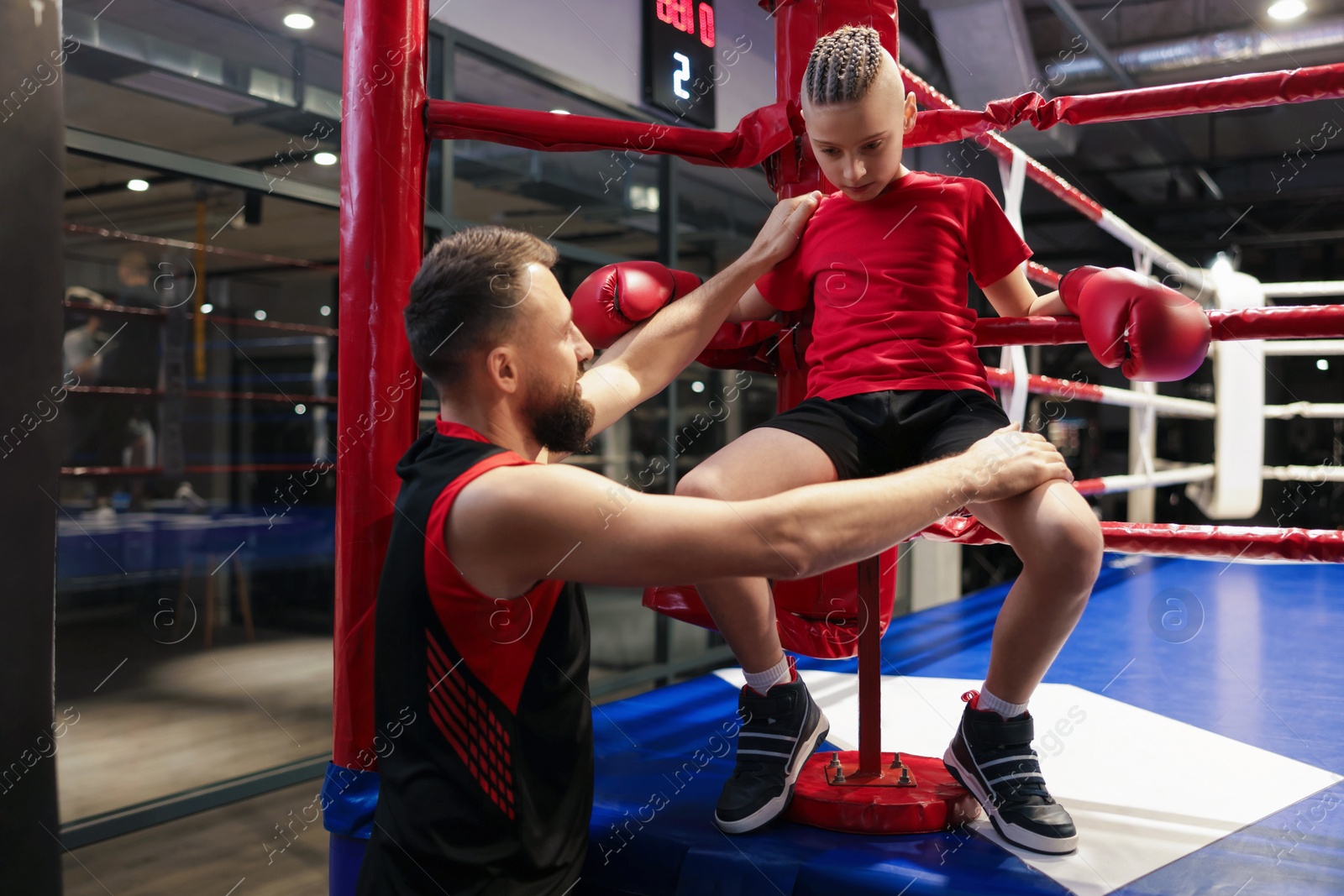 Photo of Coach encouraging boy in boxing ring corner