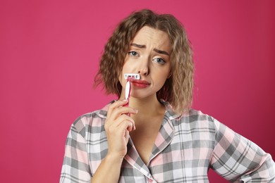 Photo of Emotional woman shaving her mustache with razor on pink background