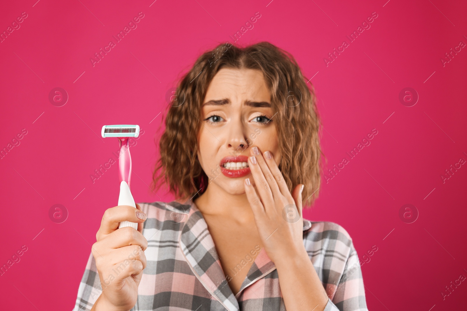 Photo of Worried woman with razor on pink background. Hair removal tool