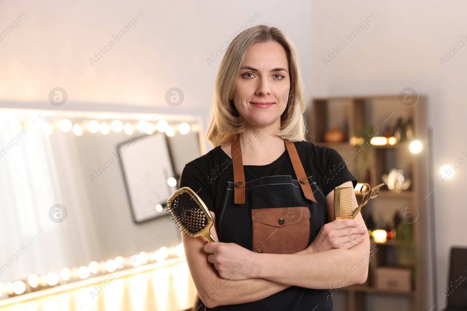 Photo of Hairdresser with brush, comb and scissors in beauty salon