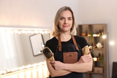 Photo of Hairdresser with brush, comb and scissors in beauty salon