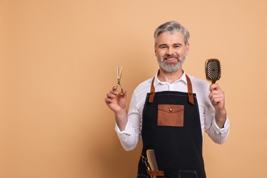 Photo of Smiling hairdresser with scissors and brush on beige background, space for text