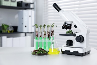 Photo of Biochemistry. Microscope, glassware with liquids and plants on white table in laboratory