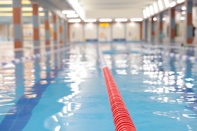 Photo of Swimming pool with clean water and lane dividers indoors, closeup