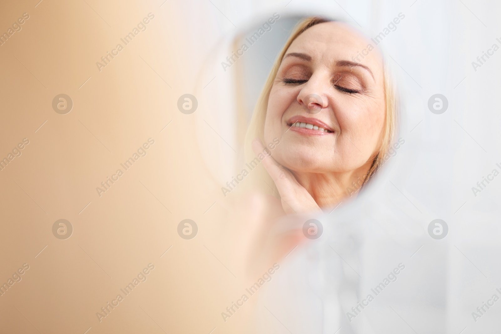 Photo of Smiling middle aged woman with round mirror on blurred background