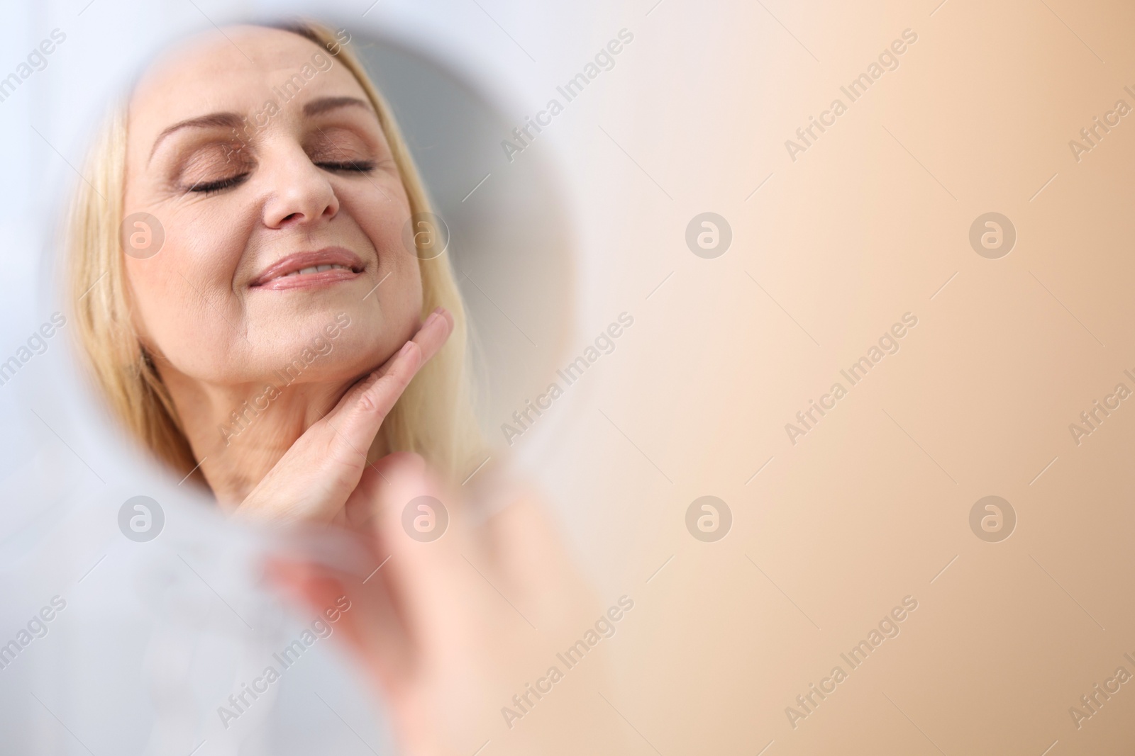 Photo of Smiling middle aged woman with round mirror on blurred background