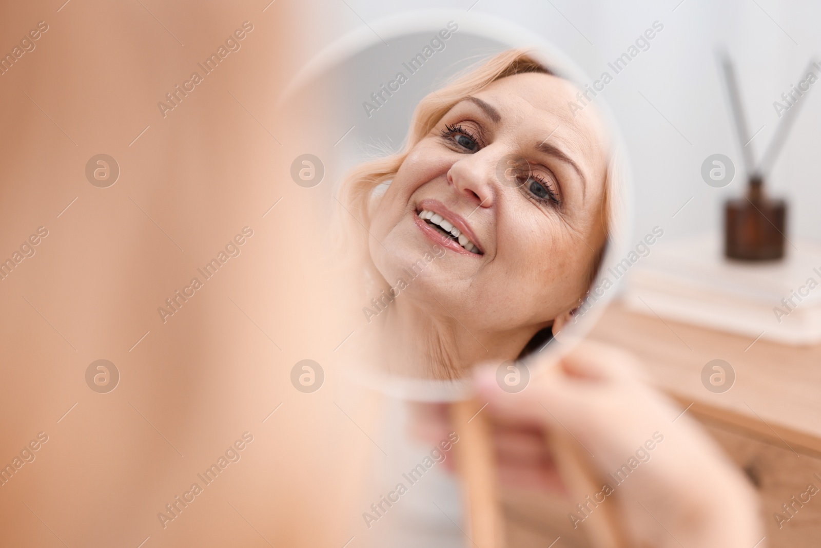 Photo of Smiling middle aged woman with round mirror at home