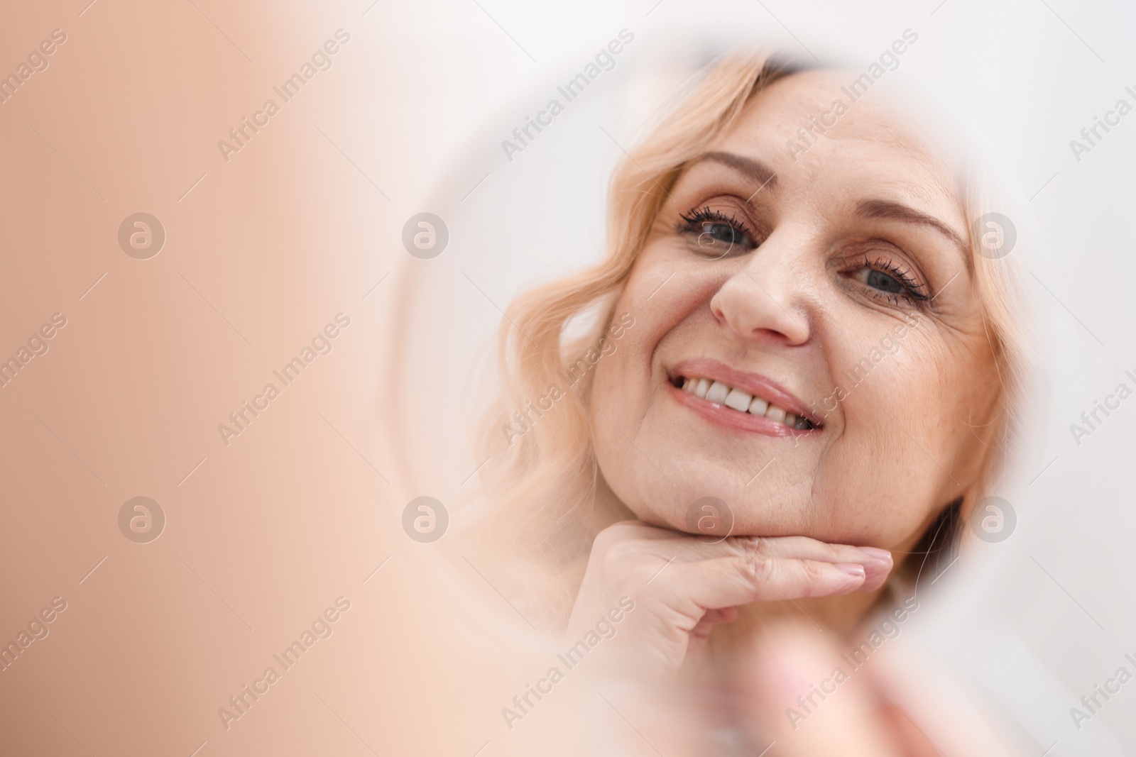 Photo of Smiling middle aged woman with round mirror on blurred background