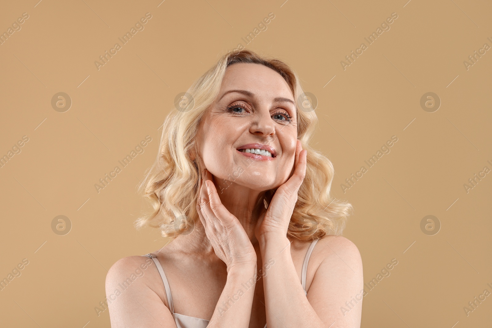 Photo of Portrait of smiling middle aged woman on beige background