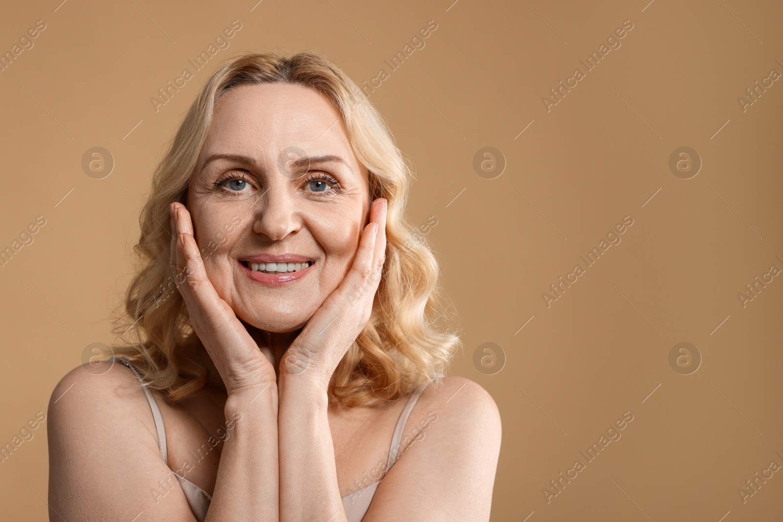 Photo of Portrait of smiling middle aged woman on beige background. Space for text