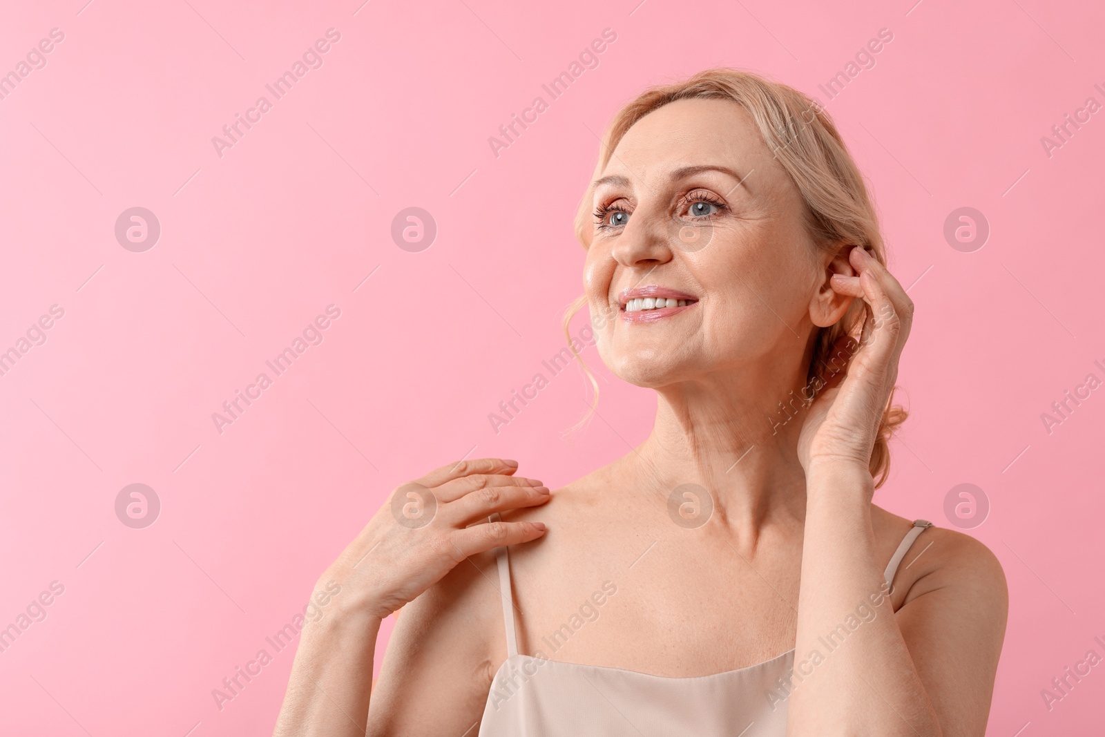 Photo of Smiling middle aged woman on pink background. Space for text