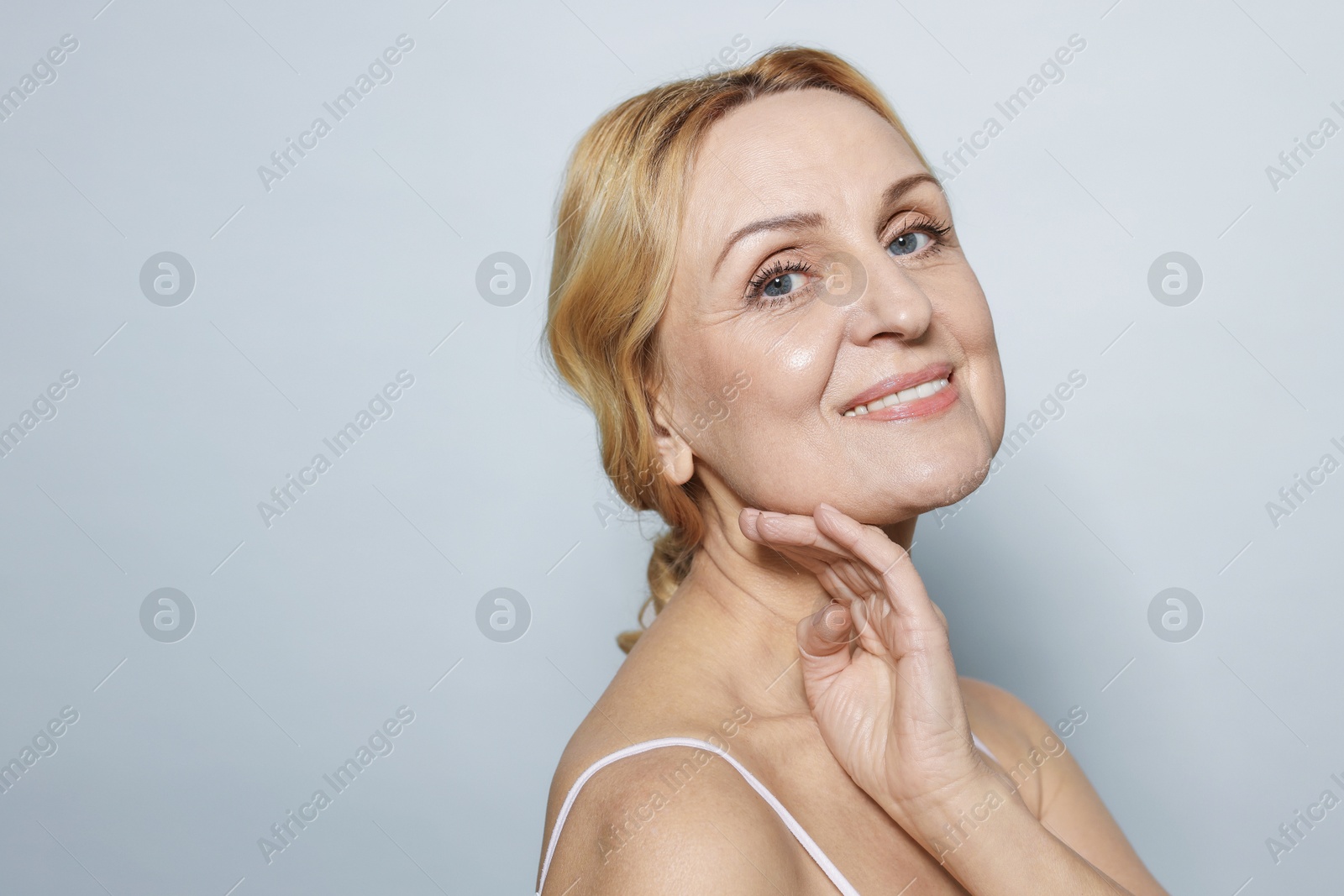 Photo of Portrait of smiling middle aged woman on grey background. Space for text