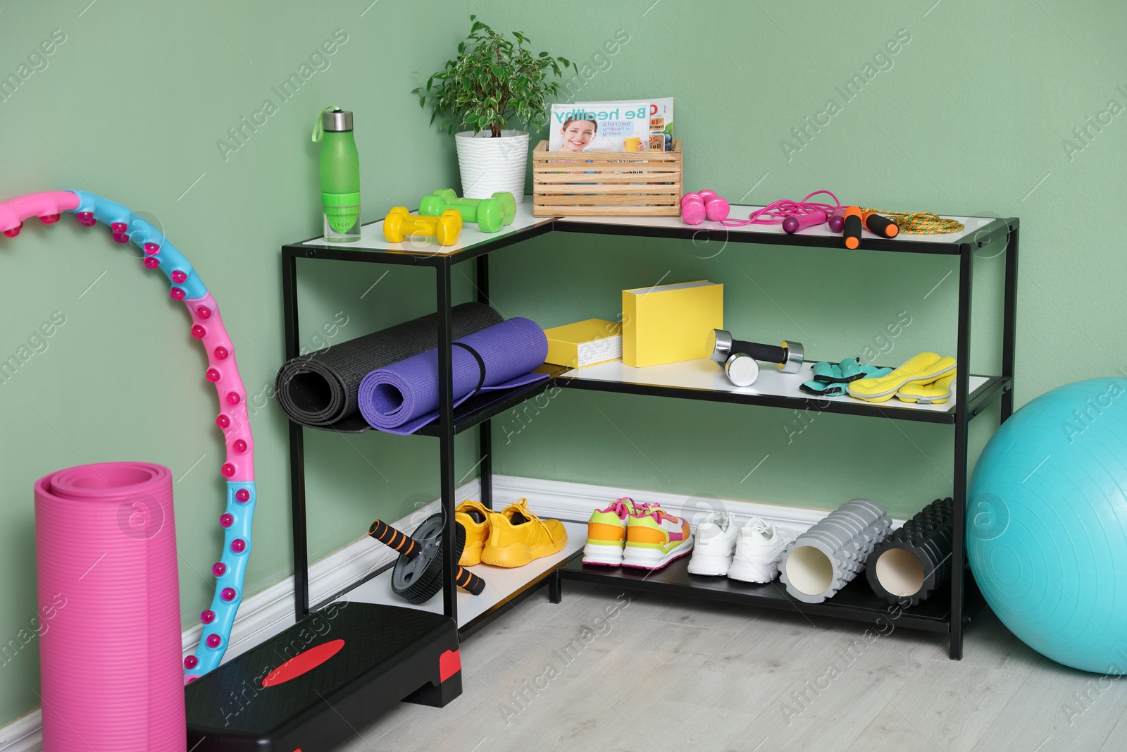 Photo of Different fitness equipment and sneakers near green wall indoors