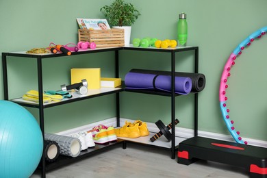 Photo of Different fitness equipment and sneakers near green wall indoors