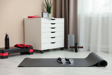 Photo of Different fitness equipment and chest of drawers indoors