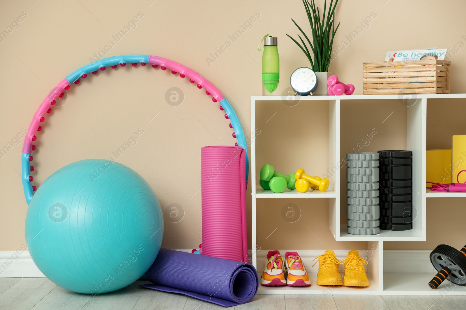 Photo of Different fitness equipment and sneakers near beige wall indoors