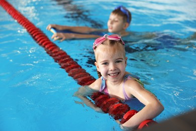 Children with goggles swimming in pool indoors, selective focus