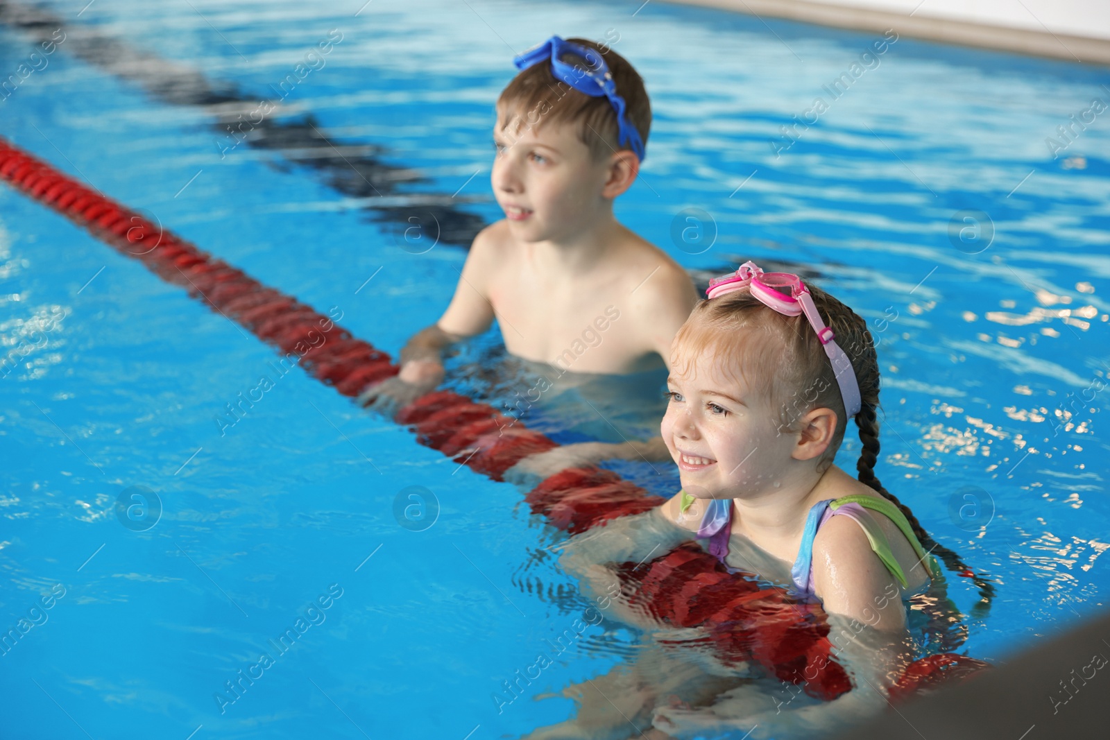 Photo of Children with goggles swimming in pool indoors, selective focus