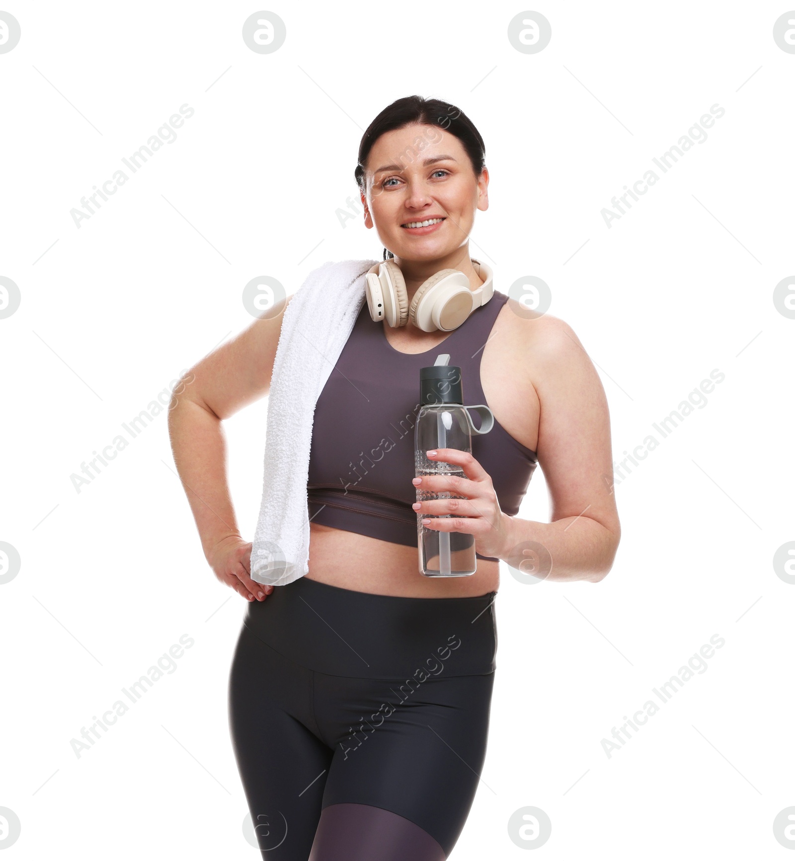 Photo of Plus size woman in gym clothes with water bottle, headphones and towel on white background