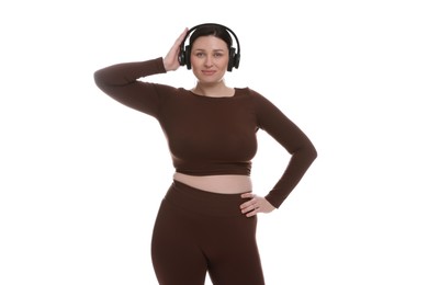 Plus size woman in gym clothes and headphones on white background