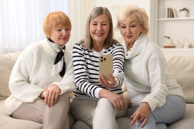 Friendship. Senior women taking selfie on sofa at home