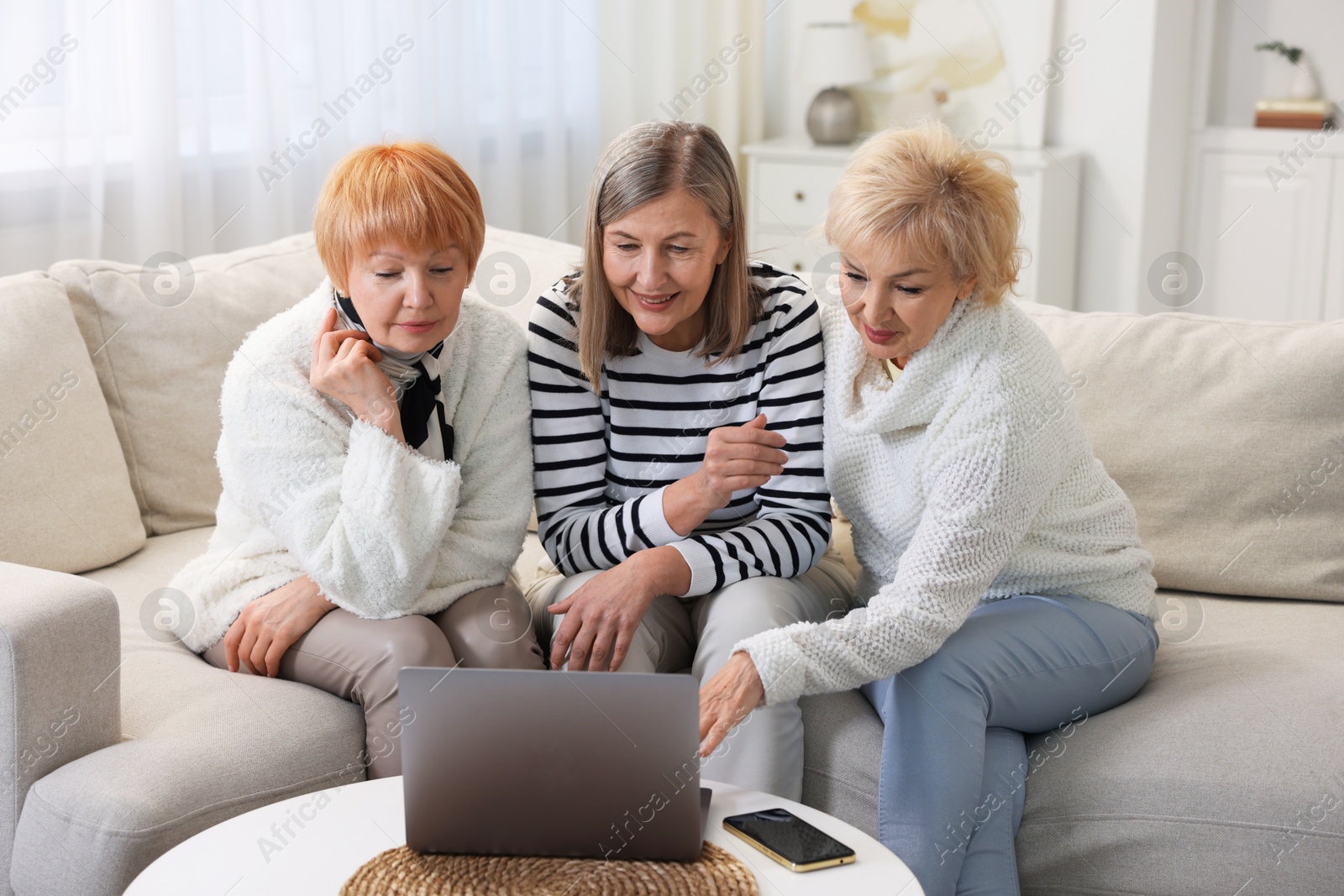 Photo of Friendship. Senior women watching something on laptop at home