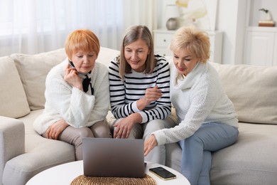 Friendship. Senior women watching something on laptop at home