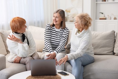 Photo of Friendship. Senior women spending time together on sofa at home