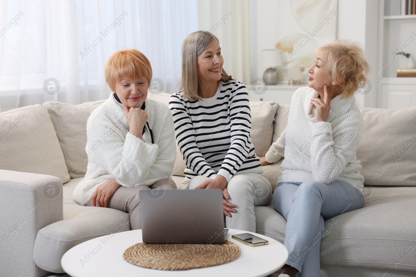 Photo of Friendship. Senior women watching something on laptop at home